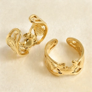 Detailed view of two gold crab rings with hollow carvings on white silk fabric