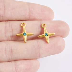 Close-up of golden stainless steel star charms with blue rhinestones held for size comparison