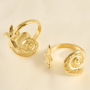 Detailed macro view of golden starfish and conch shell open rings on satin fabric