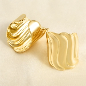 Detail of gold-plated earrings featuring modern wave textures and a polished finish