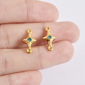 Macro view of gold four-pointed star jewelry charms with blue zircon inlay on finger