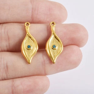 Detail of gold leaf charms with blue rhinestones and textured metal surface