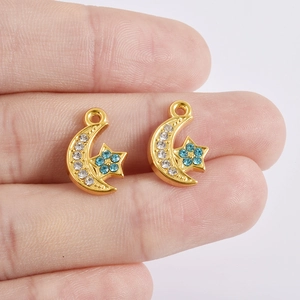 Pendentif étoile et lune dorée avec cristaux bleus et blancs sur le bout des doigts