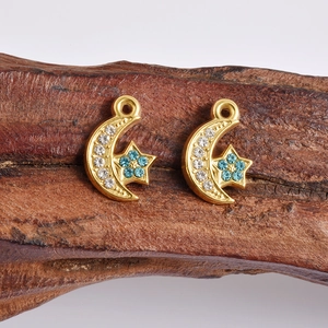 Vue macro de breloques dorées lune et étoile avec cristaux bleus et blancs pour bijoux DIY