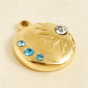 Macro detail of a 18k gold-plated sun-shaped pendant with blue and white zircon inlays