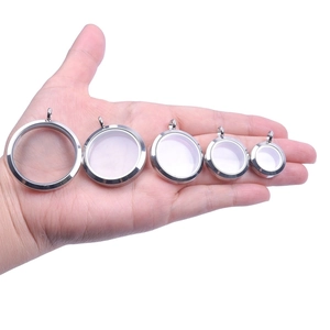 Polished stainless steel round floating locket pendants in five sizes on a palm