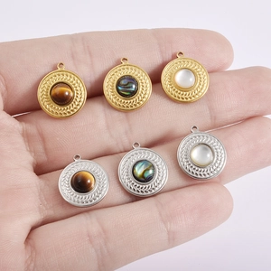 Close-up of circular 18k gold and silver pendants with shell inlay and wheat pattern