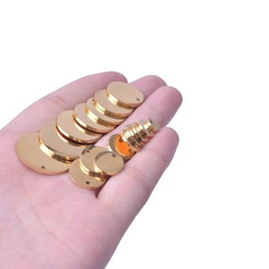 Polished gold stainless steel round tags in various sizes held in hand for jewelry making
