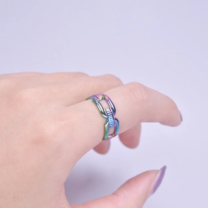 Macro shot of chain-link geometric rainbow titanium steel ring on index finger