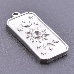 Vue macro d'un pendentif rectangulaire en acier inoxydable avec reliefs soleil et lune