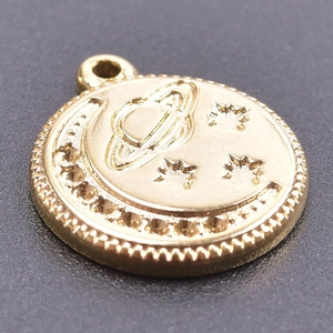 Macro shot of gold celestial pendant with embossed moon, Saturn, and stars detail