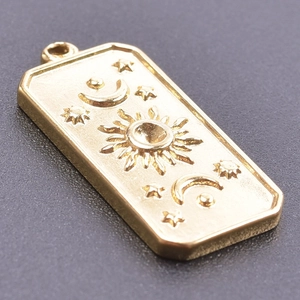Vue rapprochée d'un pendentif céleste doré avec relief soleil et lune en métal