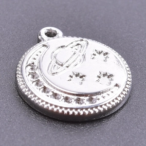 Close-up of silver celestial pendant featuring moon, Saturn, and star relief details