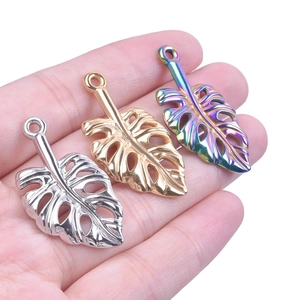 Gros plan de pendentifs feuilles de monstera en argent, or et couleurs arc-en-ciel