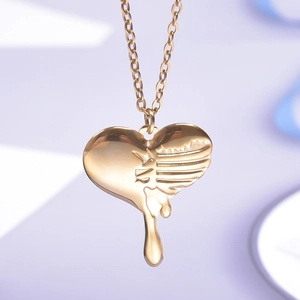 Close-up of golden heart pendant with fluid melt design and relief wing texture