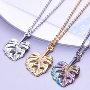Détail de pendentifs feuille de monstera en or argent et arc-en-ciel sur chaînes