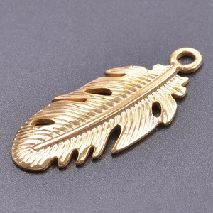 Détails d'un pendentif plume en acier inoxydable doré aux textures délicates