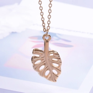 Macro d'un pendentif feuille dorée en acier inoxydable avec chaîne fine élégante