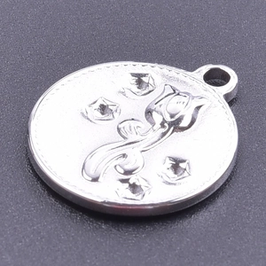 Détail macro d'un pendentif rond en acier inoxydable argenté gravé de tulipes et d'étoiles