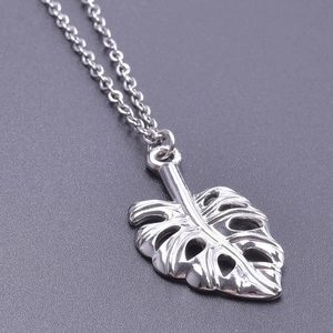 Détail macro du pendentif feuille de monstera en argent poli avec nervures évidées