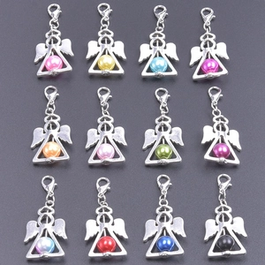 Detail of 12 colors of angel wing pendants with pearls and lobster clasps on grey background