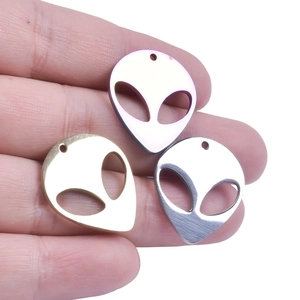 Detailed view of alien head charms in rainbow, gold, and silver on a fingertip