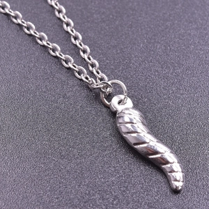 Macro detail of silver stainless steel chili pendant with intricate spiral texture and chain