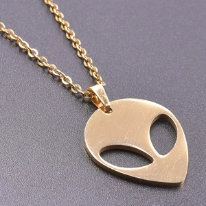 Macro shot of 18K gold-plated alien head pendant with cutout eyes on a delicate link chain