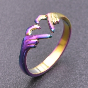 Macro shot of rainbow-colored titanium steel ring featuring a creative hand heart gesture