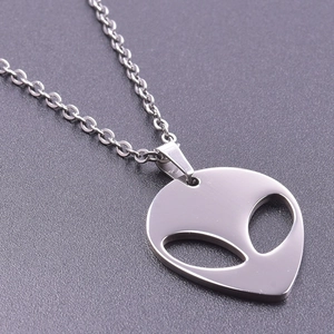 Detailed macro view of a silver alien pendant featuring hollow eyes and a delicate cross chain