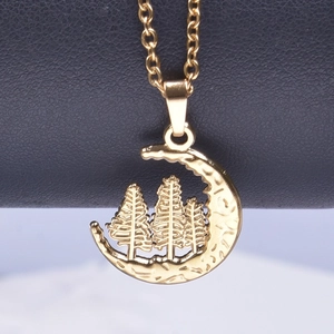Macro shot of gold crescent moon necklace with intricate pine tree engraving and texture