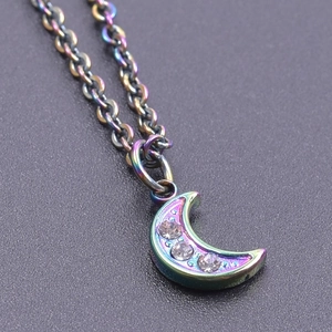 Macro view of iridescent 18K gold crescent moon pendant with three inlaid zircons
