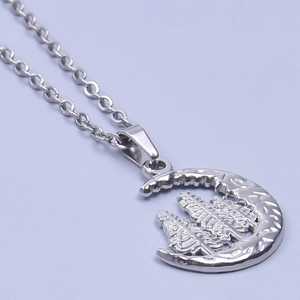 Detailed macro view of silver moon pendant with pine tree engraving and hammered texture