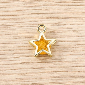 Macro view of a gold star pendant with yellow crystal filling on wooden background