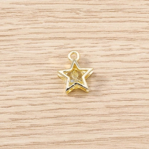Macro detail of star shaped golden pendant with yellow crystal on wooden background