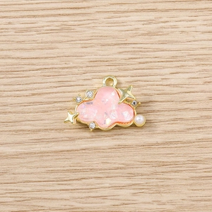 Macro shot of cloud-shaped pendant with rhinestones, gold stars, and pearl details