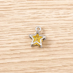 Macro shot of a silver star pendant with yellow glitter texture on a light wood background