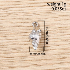 Pendentif coquillage argenté avec strass et dimensions 1,7 cm x 0,7 cm sur fond de bois clair