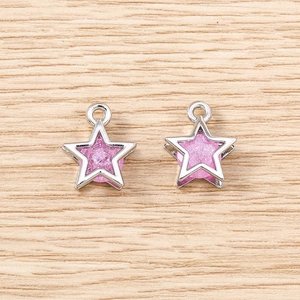 Detailed view of pink star charms with silver metal frames on light wood background