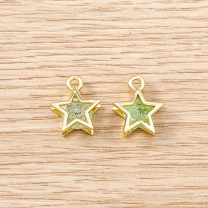 Close-up of gold star pendants with green stone inlay on a wooden background