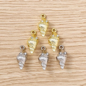 Détail de pendentifs en forme de conque dorés et argentés avec petits strass