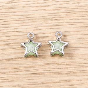 Detail of silver five-point star pendants with green resin inlay on wood background