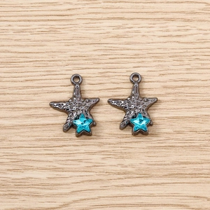 Macro shot of gun-black starfish pendants with blue rhinestones on wood background
