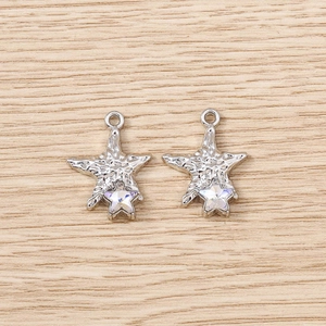 Silver starfish pendants with crystal inlay on a textured wood surface for DIY jewelry