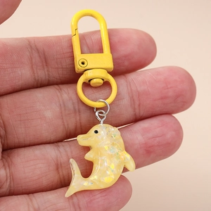 Gros plan détaillé d'un porte-clés dauphin en résine jaune avec paillettes internes