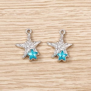 Pair of silver starfish jewelry pendants with blue star crystal and hammered metal texture