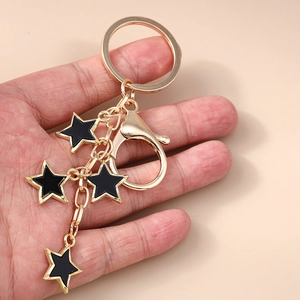 Porte-clés doré chic avec étoiles en émail noir tenu à la main pour la taille