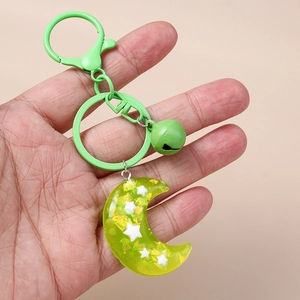 Detailed view of a green resin moon keychain with star inlay and matching metal bell