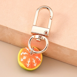 Macro shot of a lifelike orange slice keychain with a premium golden metal D-ring clasp