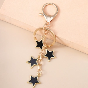 Porte-clés étoile doré avec pendentifs en émail noir sur fond rose poudré délicat